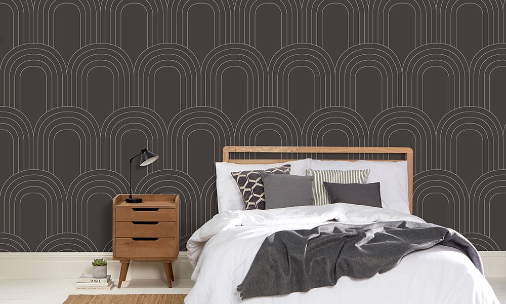 Dark grey wallpaper with a large-scale arch pattern in a bedroom setting