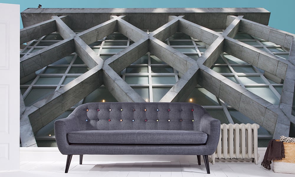 Living room with a grey sofa and brutalism wallpaper with a concrete diamond building