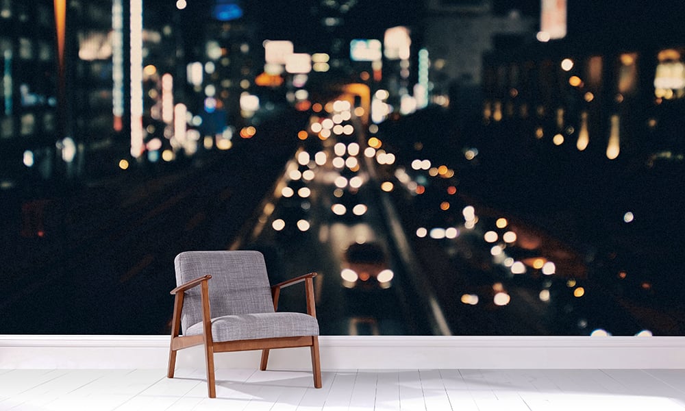 Grey chair in a living room with a lit-up citycape mural at night