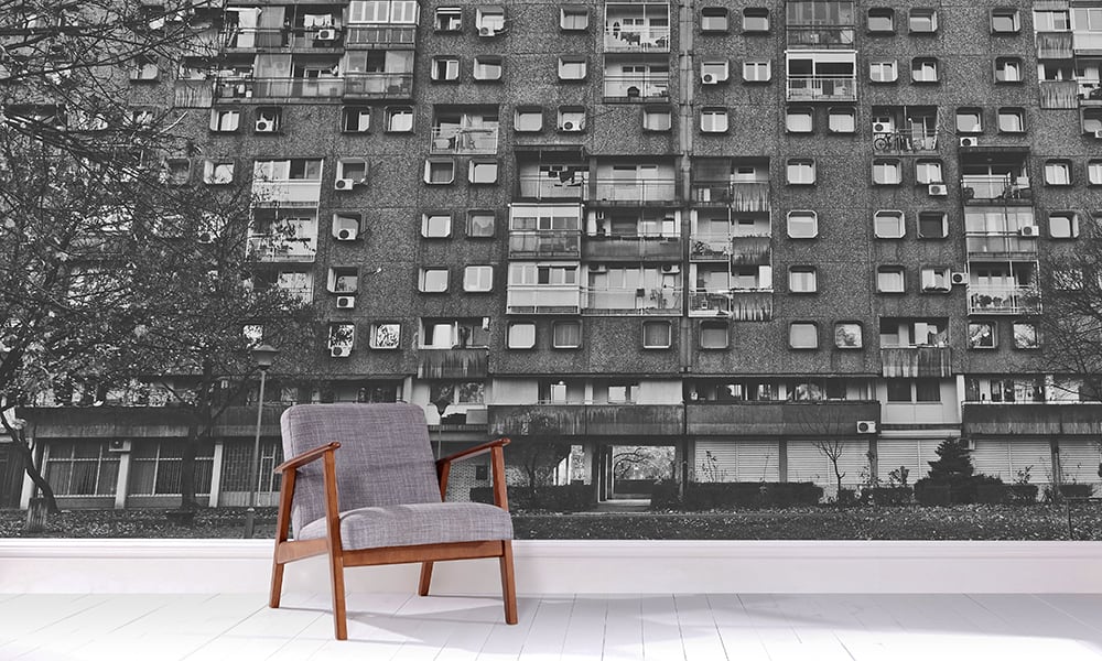 Concrete block of flats urban style wall mural in a living room with grey chair