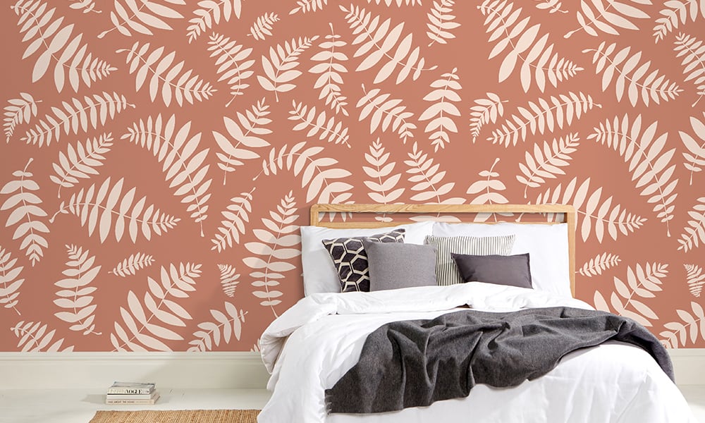 Large-scale orange leafy wallpaper design in a bedroom setting 