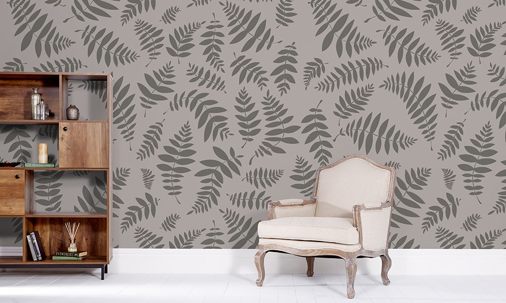 Dark grey leaf print wallpaper in a large-size pattern with a chair and bookcase