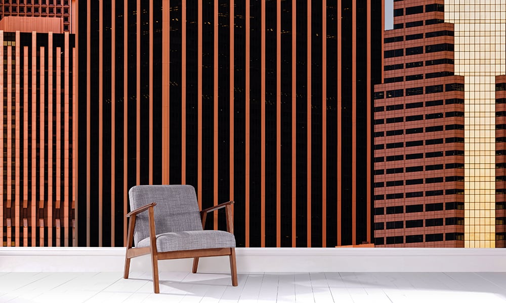 Orange and black city wall mural in a living room with grey chair
