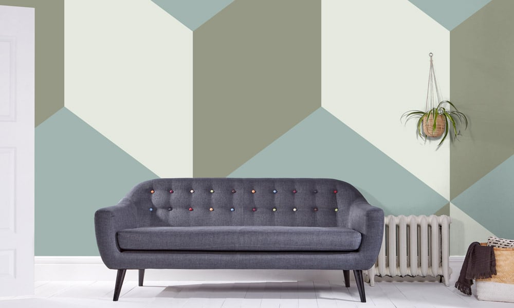 Living room with hanging planter with a sage green geometric wallpaper mural behind sofa