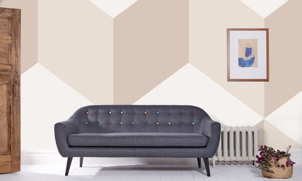 Grey sofa in living room with beige geometric wallpaper