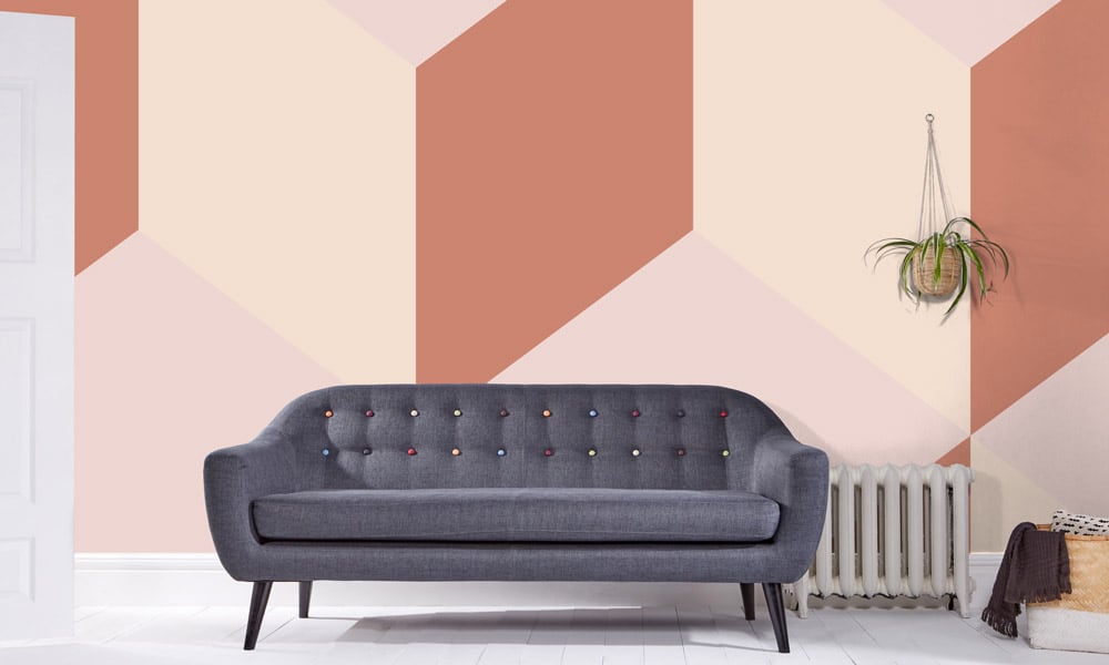 Orange and pastel pink wall mural behind a grey sofa in a living room