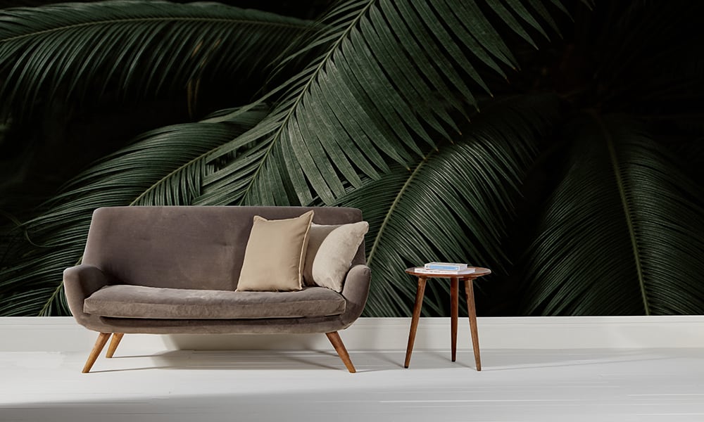 Dark palm leaf wallpaper in a mid-century modern living room