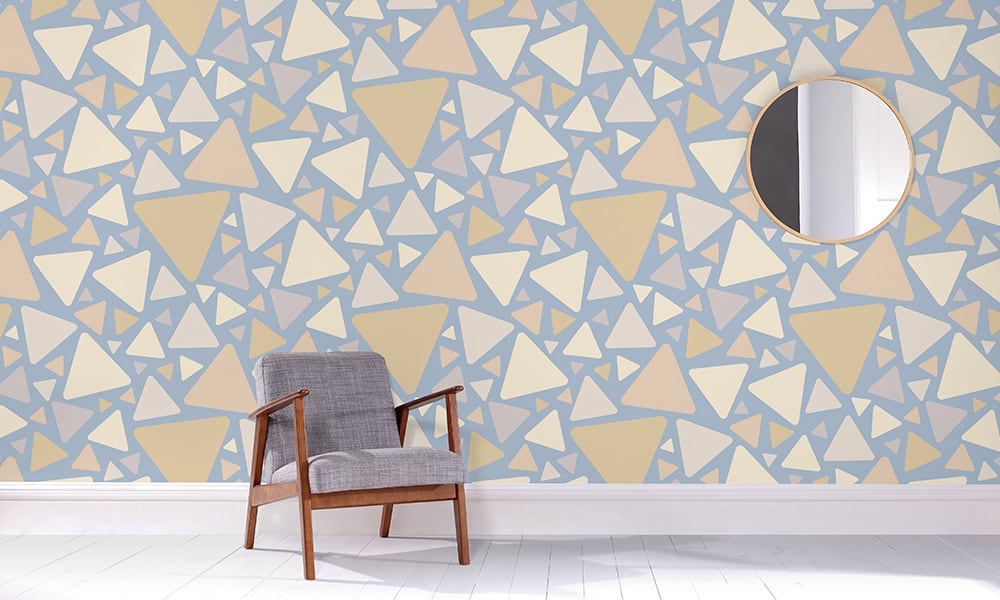 Large-scale triangular pattern in a blue and neutral colour palette in a living space with a grey chair