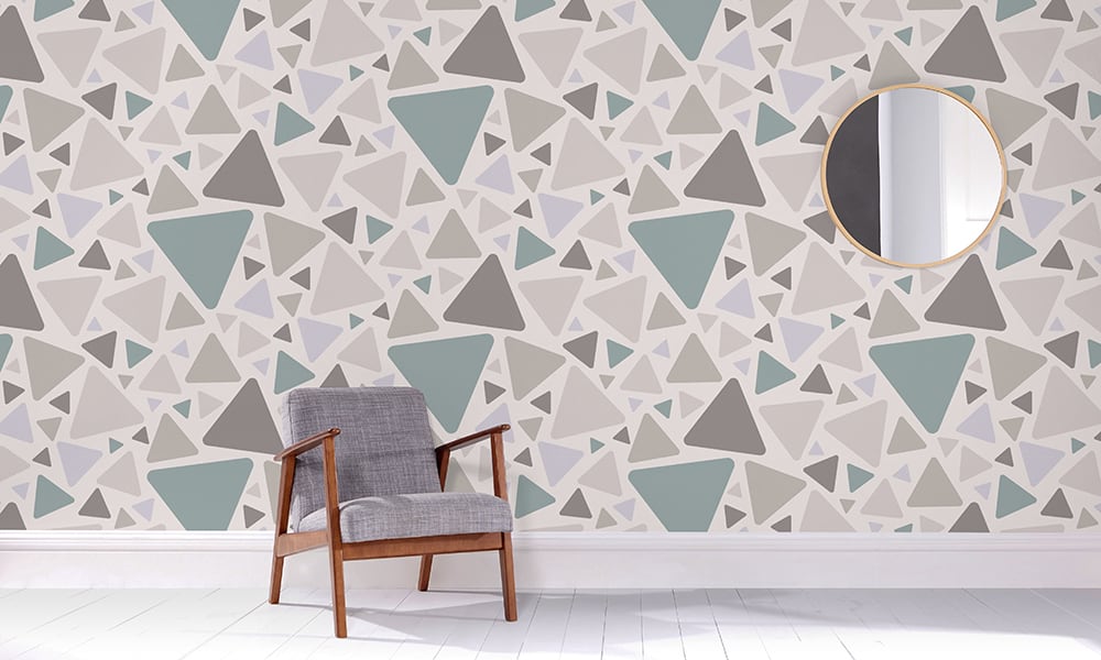 Large-scale triangular design in a grey and teal colour palette in a living space with a grey chair