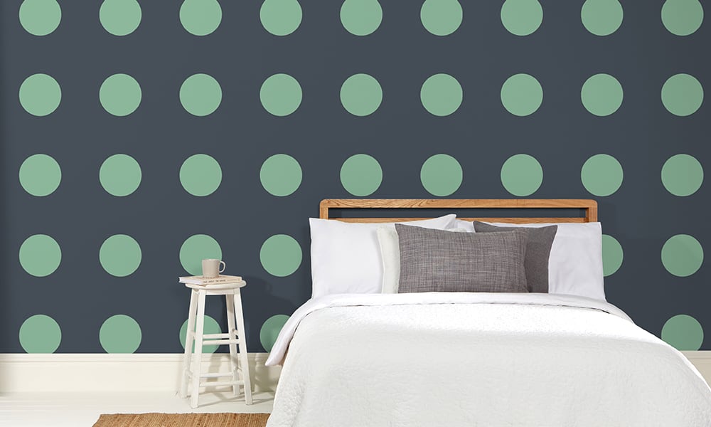 Modern polka dot navy blue and bright green wallpaper in a large pattern in a living room with grey chair