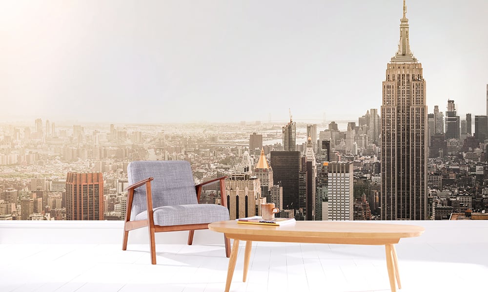 Empire state building wall mural in living room with a grey chair