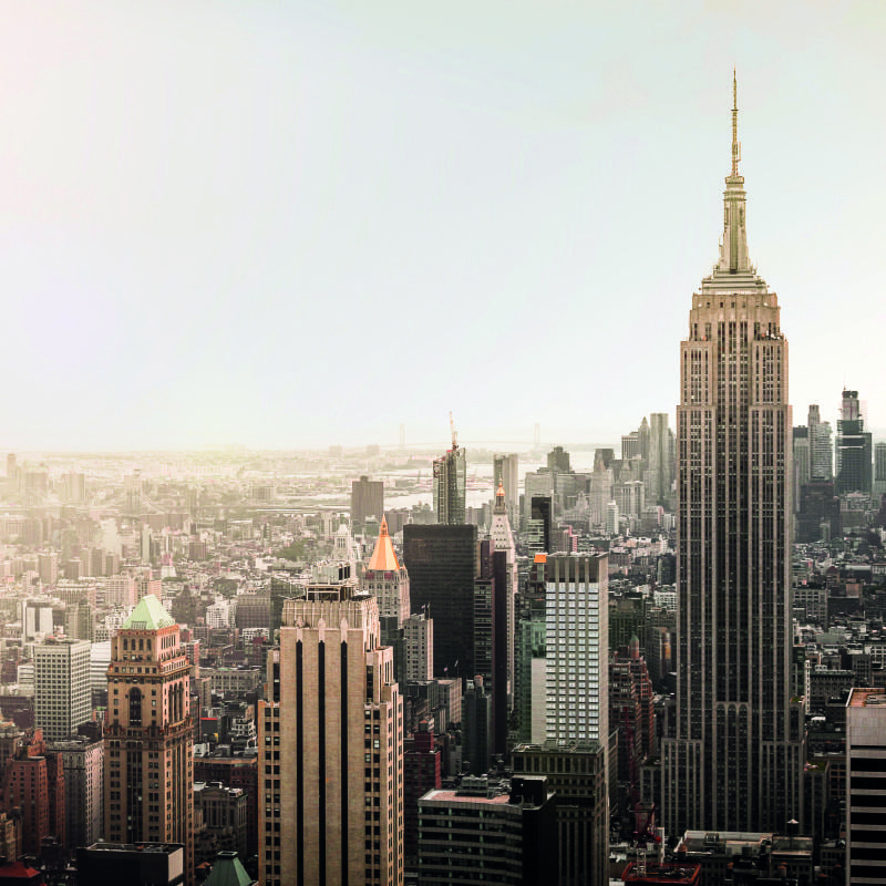 Grey chair in living room with new york city wall mural with empire state building