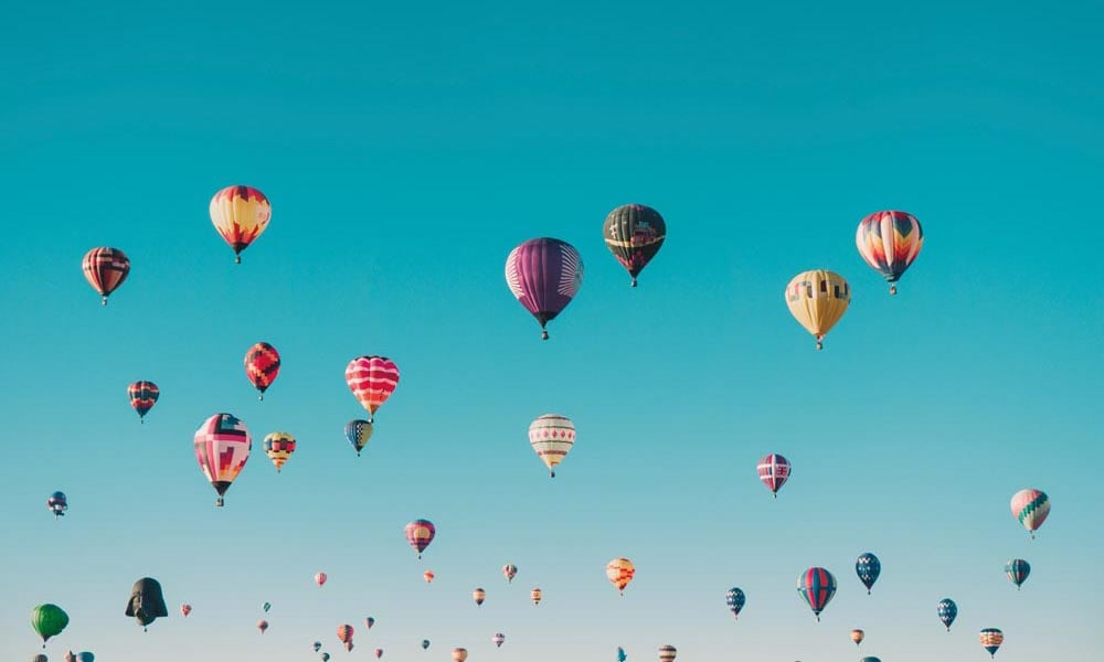 A collection of hot air balloons floating across a clear blue sky