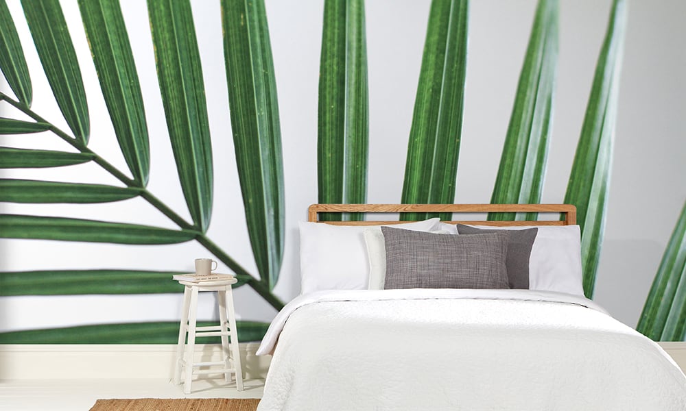Green palm leaf wall mural on a white backdrop in a modern bedroom