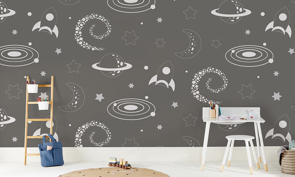 Large-scale space-themed wallpaper with rockets, stars and moons in a child's bedroom 