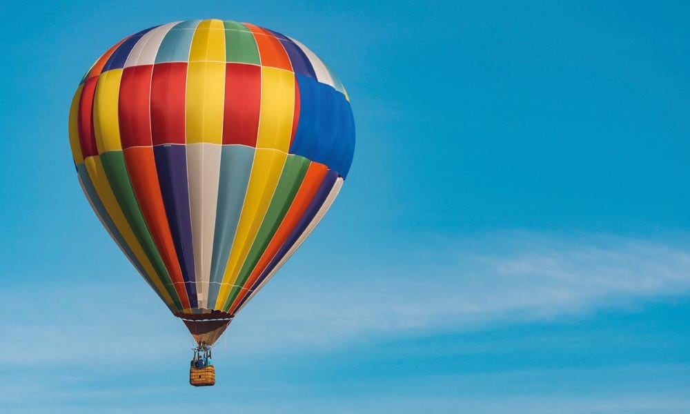 A colourful hot air balloons floating across a clear blue sky
