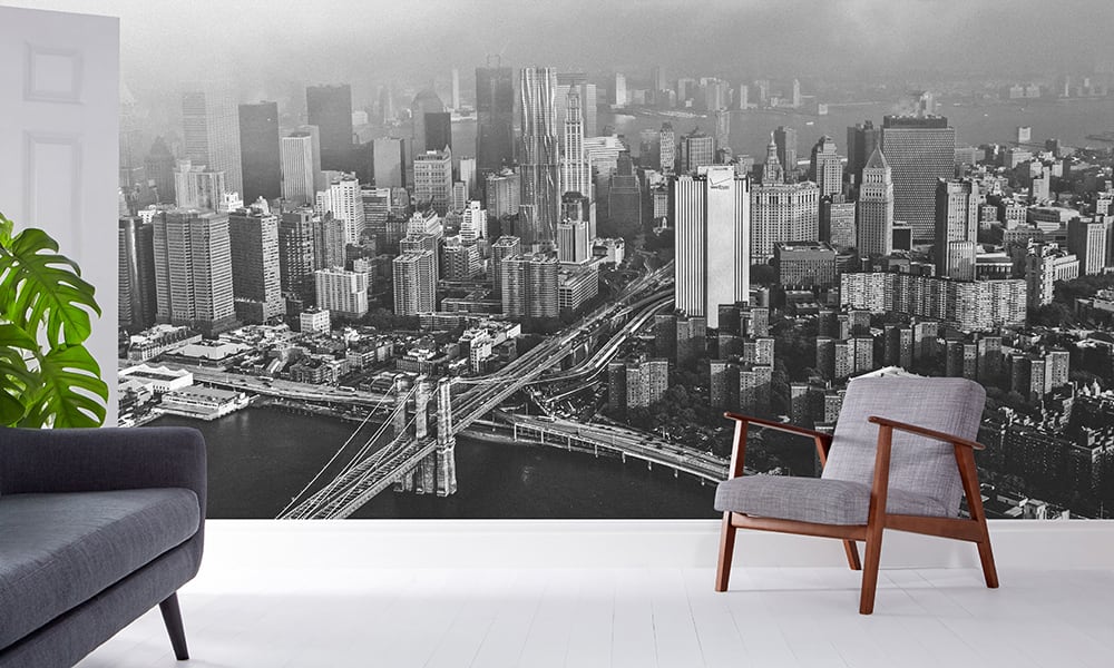 Black and white photographic wallpaper of New York in a living room with grey sofa and chair