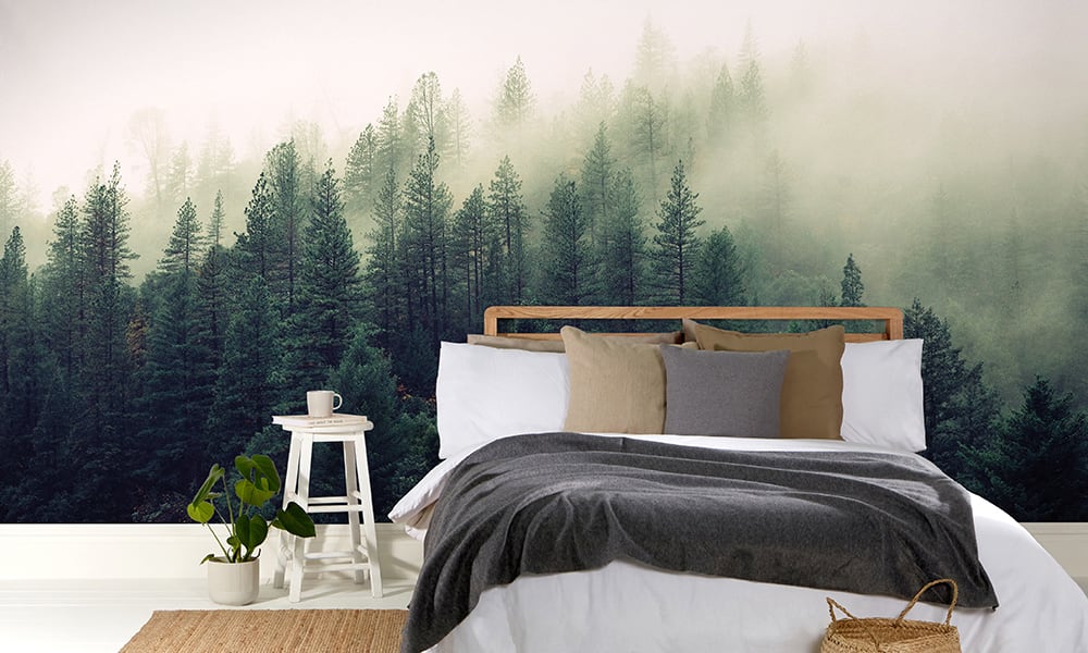 Scandi-style bedroom with a fir tree forest landscape wall mural behind bed