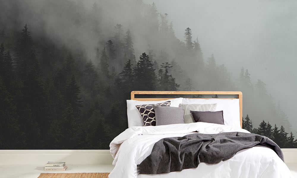 Wall mural in a bedroom featuring a misty mountain forest landscape