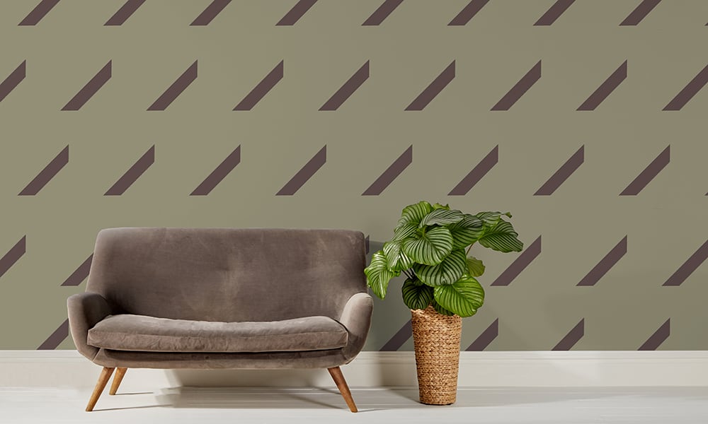 Large scale olive repeat pattern wallpaper with grey sofa and plant