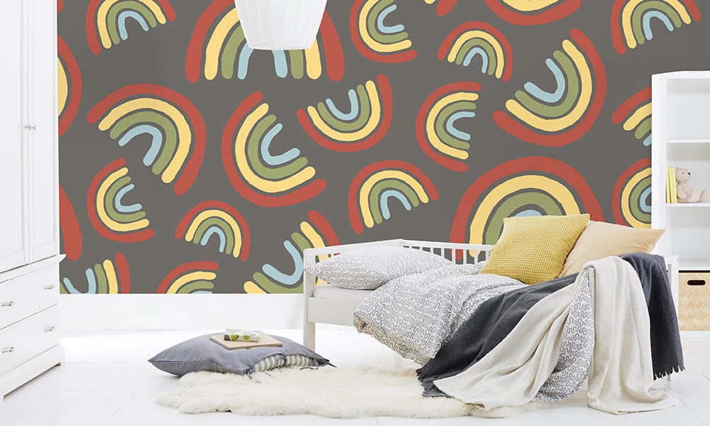 Large scale rainbow wallpaper design situated in kids bedroom in grey colourway