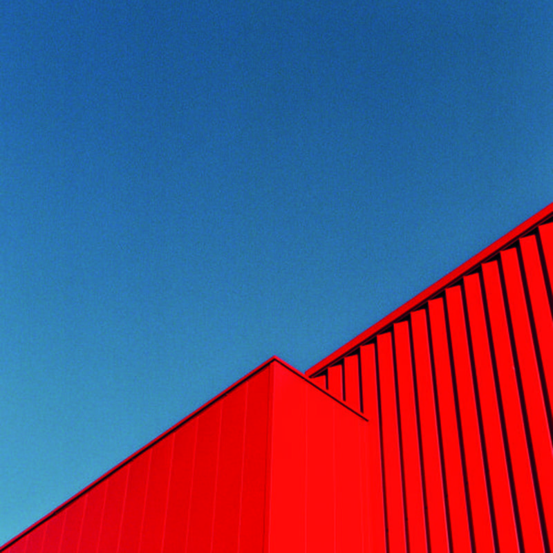Living room with grey chair with bright red abstract wall mural with blue sky