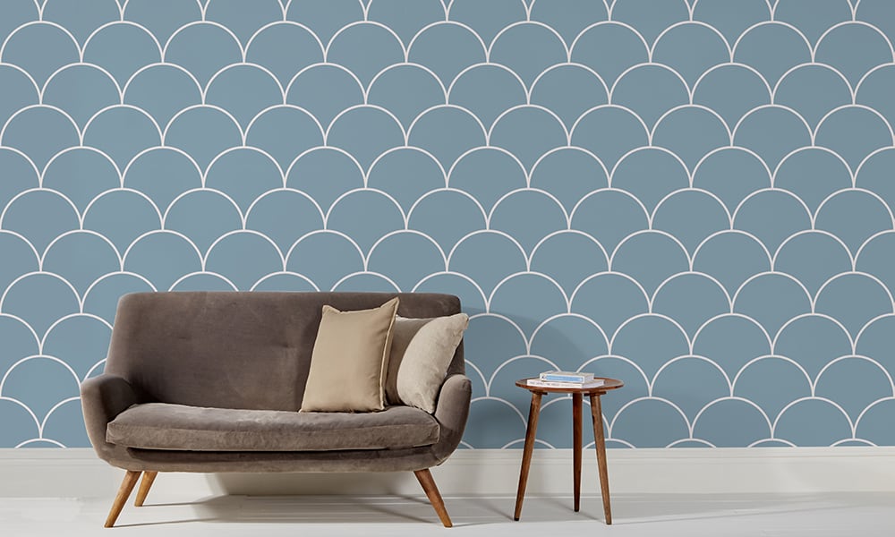 Large scale blue wallpaper design in living room with grey sofa and side table
