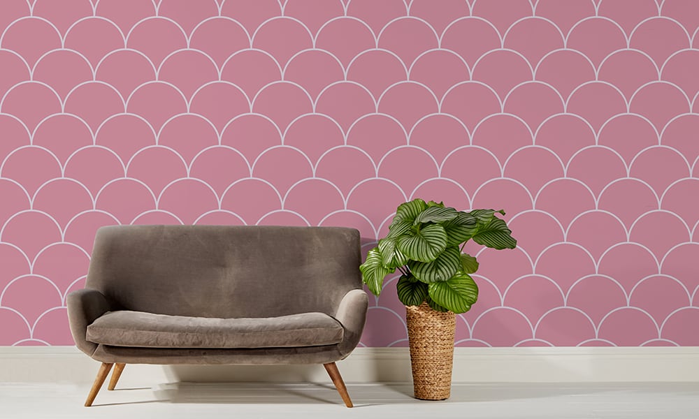 Large scale pink wallpaper design in living room with grey sofa and cheese plant