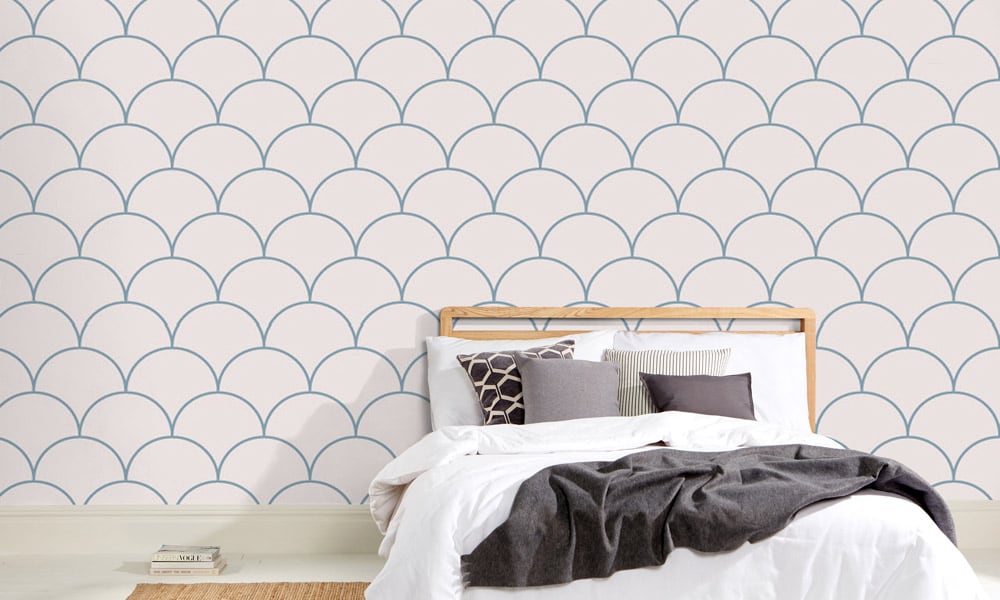 Large scale blue wallpaper design in bedroom with grey cushions and book