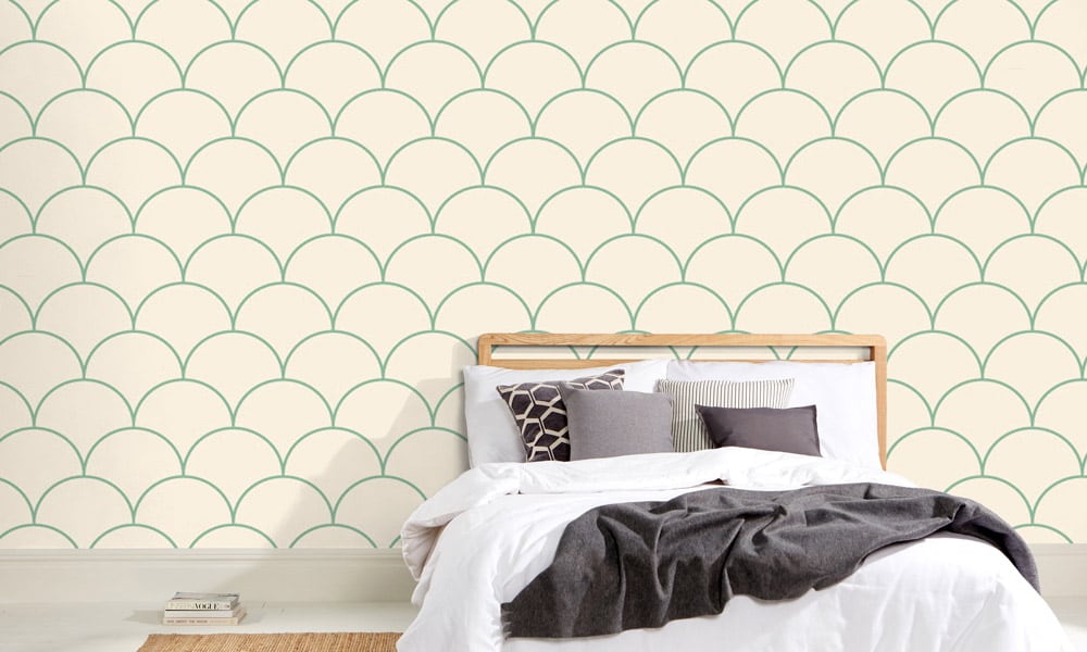 Large scale green wallpaper design in living room with grey cushions and side table
