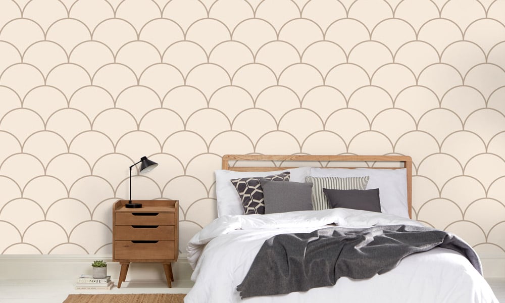 Large scale neutral wallpaper design in bedroom with grey cushions and side table