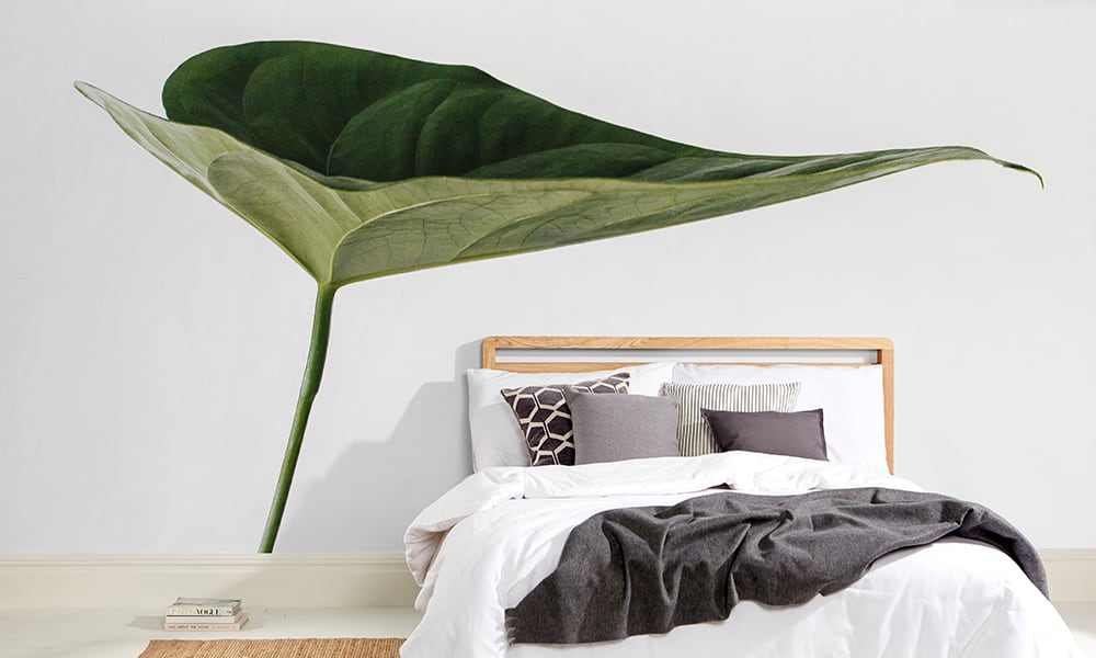Scandi-style bedroom with a large green leaf wall mural 