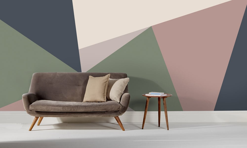 Pink, green and navy wall mural with clean lines in a modern lounge with mid-century style sofa