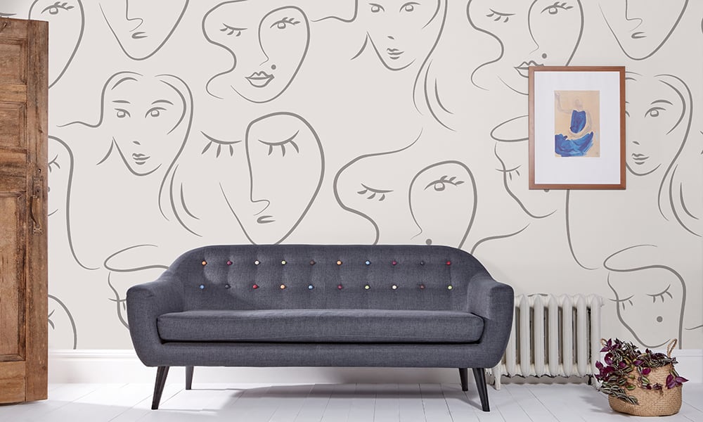 Grey toned wallpaper with abstract face pattern in living room with grey sofa