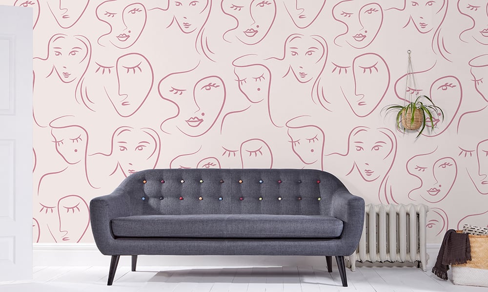 Pink abstract patterned wallpaper in living room with grey sofa